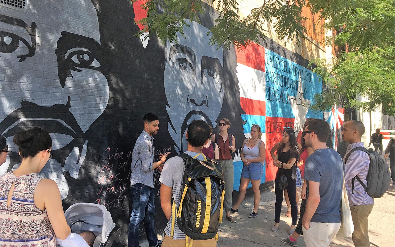 A tour group standing in front of a mural