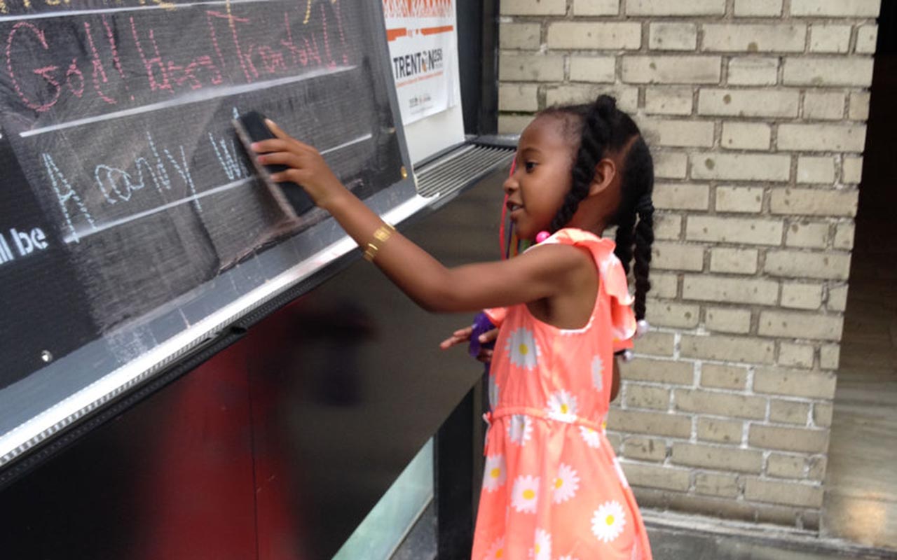 A young person writing on a chalkboard